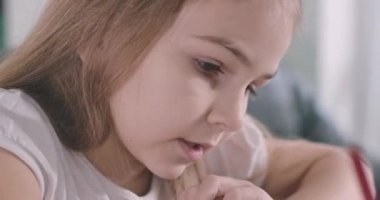 Kafkasyalı güzel bir kızın yazma ve konuşma şeklinin aşırı yakın plan yüzü. Ev ödevi yapan zeki bir okul çocuğu. Zombi neslinin portresi. Zeka, eğitim. Sinema 4k Prores Merkezi.