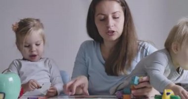İki küçük kızıyla oynayan beyaz bir annenin yakın plan portresi. Güzel sarışın kızlar günlerini aileleriyle geçirirler. Sinema 4k Prores Merkezi.