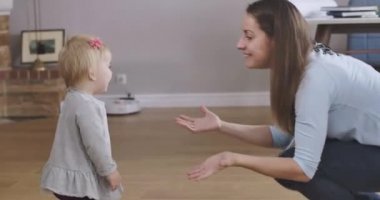 Mutlu gülümseyen bir annenin kızına yukarı gelmesini istemesi. Küçük şirin beyaz kız ilk adımlarını atıyor. Çocukluk, mutluluk, annelik sevinci. Sinema 4k Prores Merkezi.