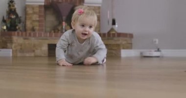 Yerde kameraya doğru sürünen gri gözlü neşeli, sarışın, beyaz bir kız bebek. Sevimli çocuk evde eğleniyor. Boş zaman, dinlenme, çocukluk, yaşam tarzı. Sinema 4k Prores Merkezi.