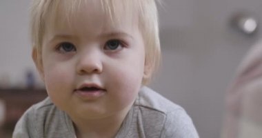 Gri gözlü, sarı saçlı ve ağzı açık yukarı bakan güzel beyaz bir kızın yakın plan yüzü. Çekici bir çocuğun portresi. Sinema 4k Prores Merkezi.