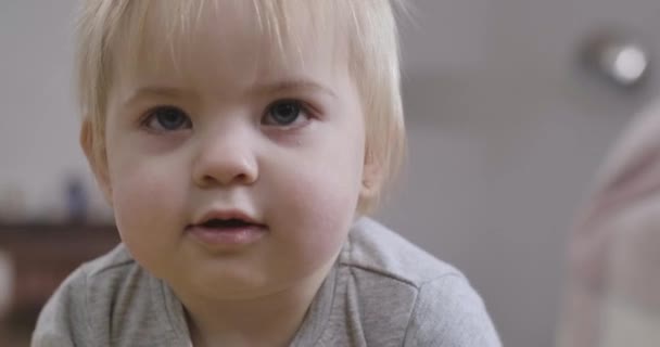 회색 눈에 금발 머리를 하고 개방 된 입으로 올려다보고 있는 아름다운 캅카스 아기의 근접 한 얼굴. 매력적 인 아이의 초상화. 영화 4K 전립선 HQ. — 비디오