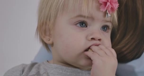 Close-up retrato de bonito menina branca mordendo biscoito e olhando para cima. Criança encantadora com olhos grisalhos e cabelos loiros. Cinema 4k ProRes HQ . — Vídeo de Stock