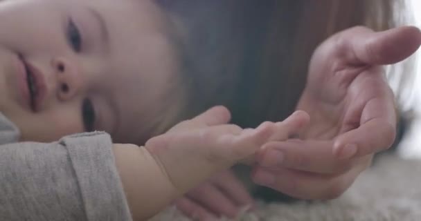 Primer plano de la rubia feliz con los ojos grises mirando a la cámara. Una joven irreconocible tocándose los dedos. Madre cuidando de su hija. Felicidad, alegría de la maternidad. Sede del cine 4k ProRes . — Vídeos de Stock