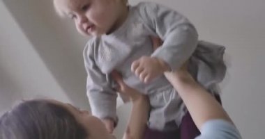 Kafkasyalı genç bir kadın havaya küçük sarışın bir kız kusuyor. Anne kızıyla oynuyor. Mutluluk, rahatlık, şefkat, yaşam tarzı Sinema 4k Prores Hq.