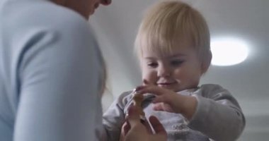 Evde anne ve kız kardeşiyle oynayan, gülümseyen, sarı saçlı, beyaz bir kızın yakın plan portresi. Çocuklarına bakan genç bir kadın. Sinema 4k Prores Merkezi.