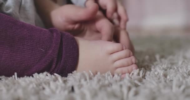 Primer plano de las manos caucásicas femeninas acariciando pequeños pies de bebé. Ternura, alegría de la maternidad, felicidad, estilo de vida. Sede del cine 4k ProRes . — Vídeo de stock