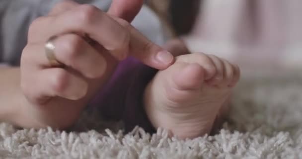 Primer plano de las manos caucásicas femeninas tocando los dedos en el pie de los pequeños bebés. Ternura, alegría de la maternidad, felicidad, estilo de vida. Sede del cine 4k ProRes . — Vídeo de stock