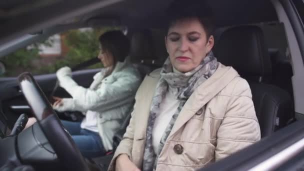 Senior Kaukasier und junge Frau sitzen in Auto Salon. reife elegante Dame beim Anlassen des Motors. Mutter und Tochter gehen im Auto einkaufen. — Stockvideo