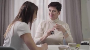 Pozitif kıdemli beyaz kadın kızına kolye veriyor. Anne genç ve güzel bir kıza kolye veriyor. İlgi, hediye, iyi ilişki, mutluluk..
