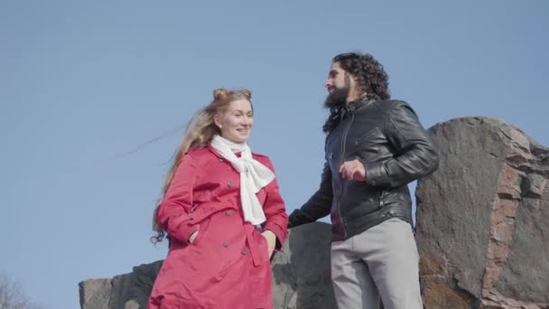 Retrato de la hermosa mujer rubia hablando con su novio hippie al aire libre. Pareja joven despreocupada citas en el parque de otoño. Gente positiva en ropa casual descansando . — Vídeo de stock