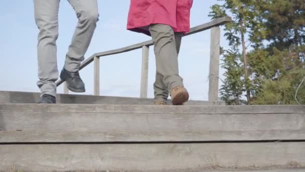 Cámara siguiendo a los hombres y las piernas de las mujeres que caminan por las escaleras al aire libre. Pareja joven paseando en el parque de otoño. Citas, romance, unión, unión . — Vídeos de Stock