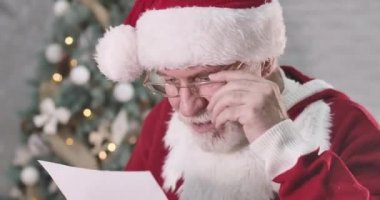 Noel Baba 'nın mektubu okuyup kameraya bakıp kafasını sallamasına şaşırmış. Beyaz sakallı, yaşlı beyaz bir adam, şimdiki zamandan bihaber. Sinema 4k Prores Merkezi.