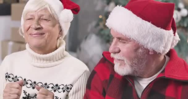 目を閉じてクリスマスツリーの下に座って肯定的な白人の老夫婦のクローズアップ。男と女が新年に願い事をする前夜。希望休日お祝いCinema 4k Prores｜Hq. — ストック動画