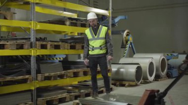 Tramvay kullanan çelik metal levhalar taşıyan bir işçi. Kasklı ve yelekli beyaz adam meslektaşını selamlıyor. Metal üretim fabrikası çalışanları, meslek, meslek, iş.