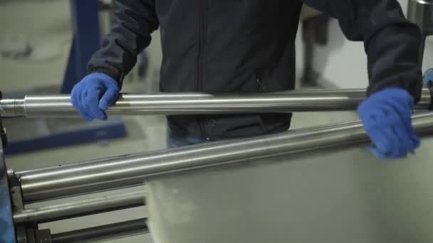 Mannelijke handen zetten staalplaat in machine voor verwerking. Man in werkhandschoenen met behulp van apparatuur voor de productie van buizen. Staalindustrie, industrie, productie. — Stockvideo