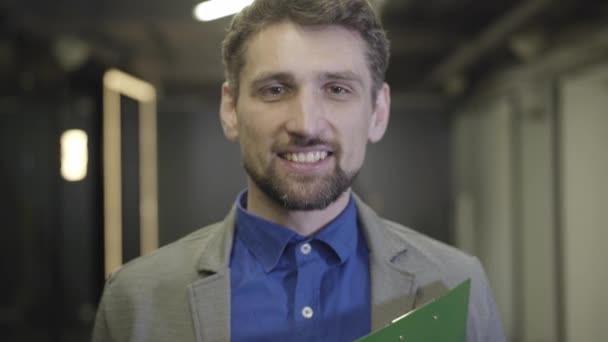 Camera moving away from handsome Caucasian mans face. Portrait of young man in business suit looking at camera and smiling. Office worker, CEO, manager. — Stock Video