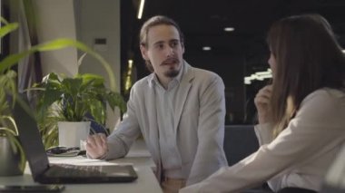 Pozitif genç beyaz ofis çalışanları konuşuyor, el sıkışıyor ve gülümsüyor. Neşeli adam ve kadın açık uzay ofisinde iş konuşuyorlar. Yönetim, Ceo, takım çalışması..