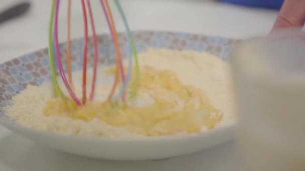 Close-up of flour mixed with eggs. Caucasian female hands using whisk to mix ingredients for bakery. Mother or grandmother baking at home. Hobby, leisure activity. — Stock Video