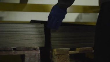 Erkek ellerinin yığından çelik levha çıkardığı yakın çekim. Üretim alanında depolanan üretim veya materyalleri hazırlayın. Çelik endüstrisi, üretim alanı, çelik fabrikası.
