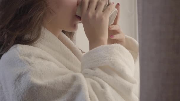 Extreme close-up van een mooie blanke jonge vrouw die 's morgens koffie drinkt en lacht. Vrolijk brunette meisje genieten van het begin van een nieuwe dag thuis. Lifestyle, vrije tijd, geluk. — Stockvideo