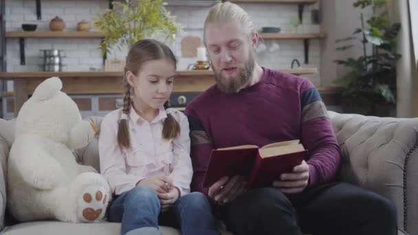 Portrait de heureux père et fille caucasiens lisant ensemble à la maison. adolescent brunette fille fermeture livre et donnant père haute cinq. Famille amicale s'amuser à l'intérieur . — Video