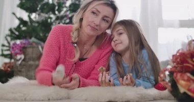 Sarışın, beyaz bir kadın ve esmer bir kızın portresi. Kafaları birbirine yakın ve konuşuyorlar. Anne ve kızı yeni yıl arifesini evde birlikte geçiriyorlar. Sinema 4k Prores Merkezi.