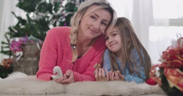 Närbild av unga kaukasiska kvinna pratar med brunett flicka äter kaka. Mor och dotter firar julafton hemma. Cinema 4k Prores Hq. — Stockvideo