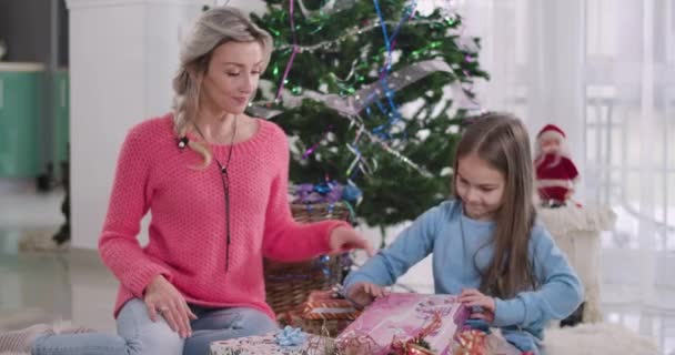 Překvapená běloška otevírá dárkovou krabici, matka se na ni dívá. Šťastná žena tráví Silvestr s dcerou doma. Vánoce, svátky, štěstí. Cinema 4k Prores Hq. — Stock video