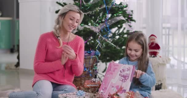 Positiv vit blond mamma pratar med dotter som barn tittar in i presentförpackning. Lycklig flicka får julklapp från mamma. Njutning, helgdagar, nyårsafton. Cinema 4k Prores Hq. — Stockvideo