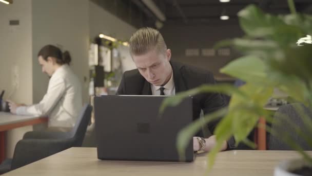 Retrato de close-up do homem caucasiano ruivo olhando para a tela do laptop e digitando no teclado. Trabalhador de escritório bem sucedido no escritório de espaço aberto. Gestão, trabalho, CEO . — Vídeo de Stock