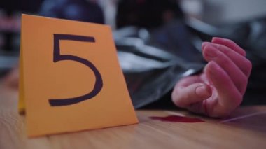 Tabela yakın plan, beş numara kan gölünde beyaz kadın elin yanında duruyor. Suç mahalli, cinayet, suikast.