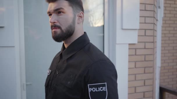 Die Kamera folgt dem jungen kaukasischen Detektiv, der an die Eingangstür klopft, sie öffnet, die Waffe nachlädt und eintritt. tapferer Polizist bei der Arbeit. Strafverfolgung, Polizeistreife. — Stockvideo