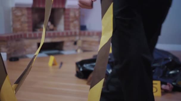 Unrecognizable police officer unfolding police tape, murdered woman lying at the background. Crime scene, detective, investigation. — Stock Video