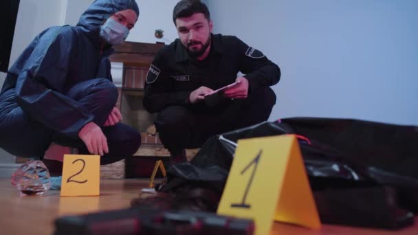 Porträtt av seriösa kaukasiska poliser som diskuterar bevis på brottsplatsen. Kriminaltekniker och poliser i uniform som arbetar på mordplatsen. Utredning, lönnmord. — Stockvideo