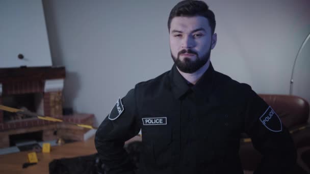 Portrait of confident Caucasian police officer with brown eyes and black hair standing at the crime scene and thinking. Young bearded detective contemplating about crime. Professional, investigation. — Stock Video