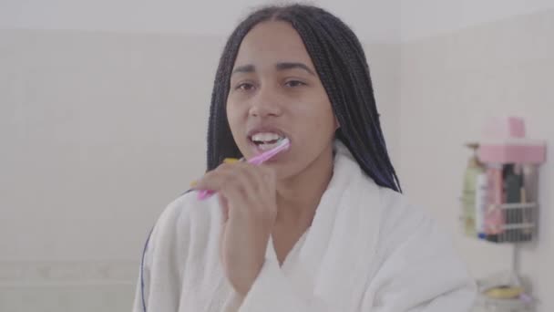 Porträtt av ung afroamerikansk kvinna med dreadlocks borsta tänderna. Söt tonårstjej som gör sig redo på morgonen. Livsstil, hälsovård, skönhet. — Stockvideo