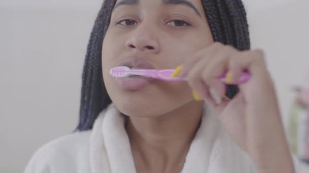 Обличчя молодої афроамериканської жінки з дредами, що чистять зуби. Красуня-підліток вранці піклується про себе. Життєпис, охорона здоров'я, краса. — стокове відео