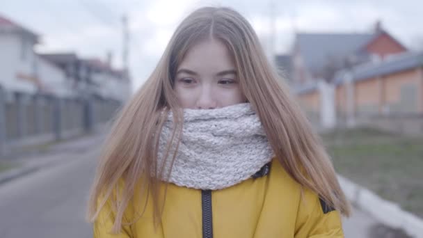 Retrato de linda chica caucásica en abrigo amarillo y bufanda blanca de pie al aire libre. Bastante adolescente mirando a la cámara como posando en el día de otoño. Belleza, estilo de vida, felicidad . — Vídeo de stock