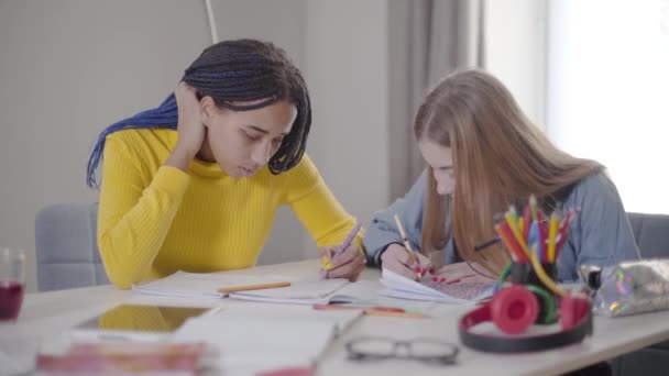 Positive kaukasische Mädchen nimmt Freunde Stift und lächelt. junge Studenten, die drinnen studieren. Lebensstil, Bildung, Lernen. — Stockvideo