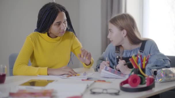 Pozitivní běloška mluví s Afroameričankou kamarádkou. Dva studenti dělají domácí úkoly. Studium, vzdělávání, inteligence. — Stock video