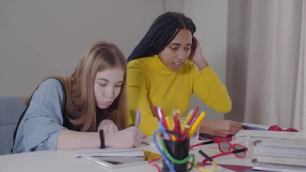 Por los amigos que hacen la tarea en casa. Chica afroamericana haciendo gesto de victoria y mostrando final de cuaderno. Estudiantes estudiando juntos. Concepto educativo . — Vídeo de stock