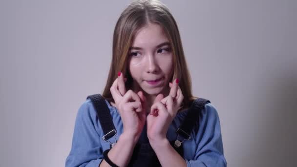 Portrait of cute Caucasian female teenager holding fingers crossed. Positive young girl waiting for something. Hope, lifestyle. — Stock Video