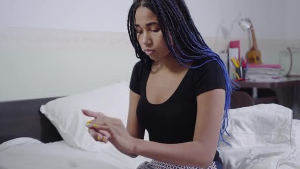 Portrait of African American girl applying hand cream. Cute teen sitting on soft white bed at home. Skin care, beauty. — Stock Video