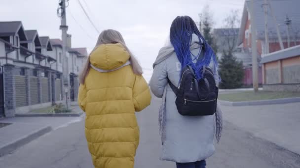 白人和非洲裔美国女孩在街上漫步的倒影。 穿着保暖衣服的朋友们在户外散步。 生活方式、友谊、休闲. — 图库视频影像