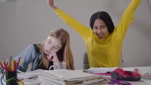 Porträtt av en afroamerikansk flicka som gör segergest och ger high five till en vit vän. Tonåringar studerar tillsammans. Utbildningsidé. — Stockvideo