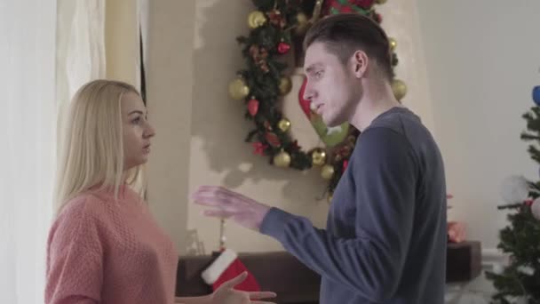 Boční pohled na krásný bělošský pár hádající se na Silvestra. Dospělý muž a žena mluví s nespokojeným výrazem ve tváři. Sváteční sezóna, problémy se vztahem. — Stock video