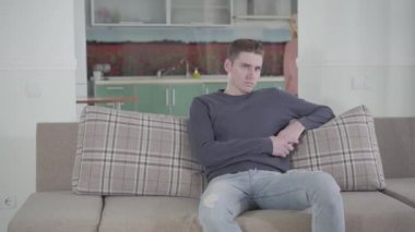 Kanepede oturan yakışıklı beyaz adamın portresi arka plandan gelen ve onu azarlayan kız arkadaşı ya da karısı gibi. İlişki sorunları, yanlış anlaşılma, çatışma.