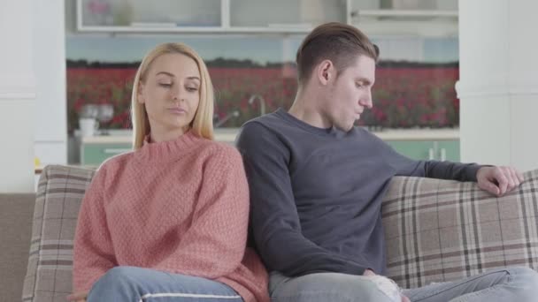 Positiv kaukasisk kvinna som ger lillfingret till make / maka för att sluta fred. Unga grälade par sitter på soffan hemma. Lycka, problem, kommunikation, nöje. — Stockvideo
