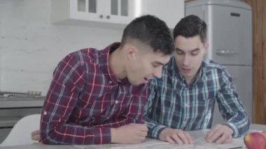 Olumlu gülümseyen beyaz adamın portresi ikiz kardeşine ziyaret etmek ve konuşmak istediği yerleri gösteriyor. Yetişkin kardeşler harita kullanarak tatil planlıyorlar. Yaşam tarzı, eğlence, turizm..